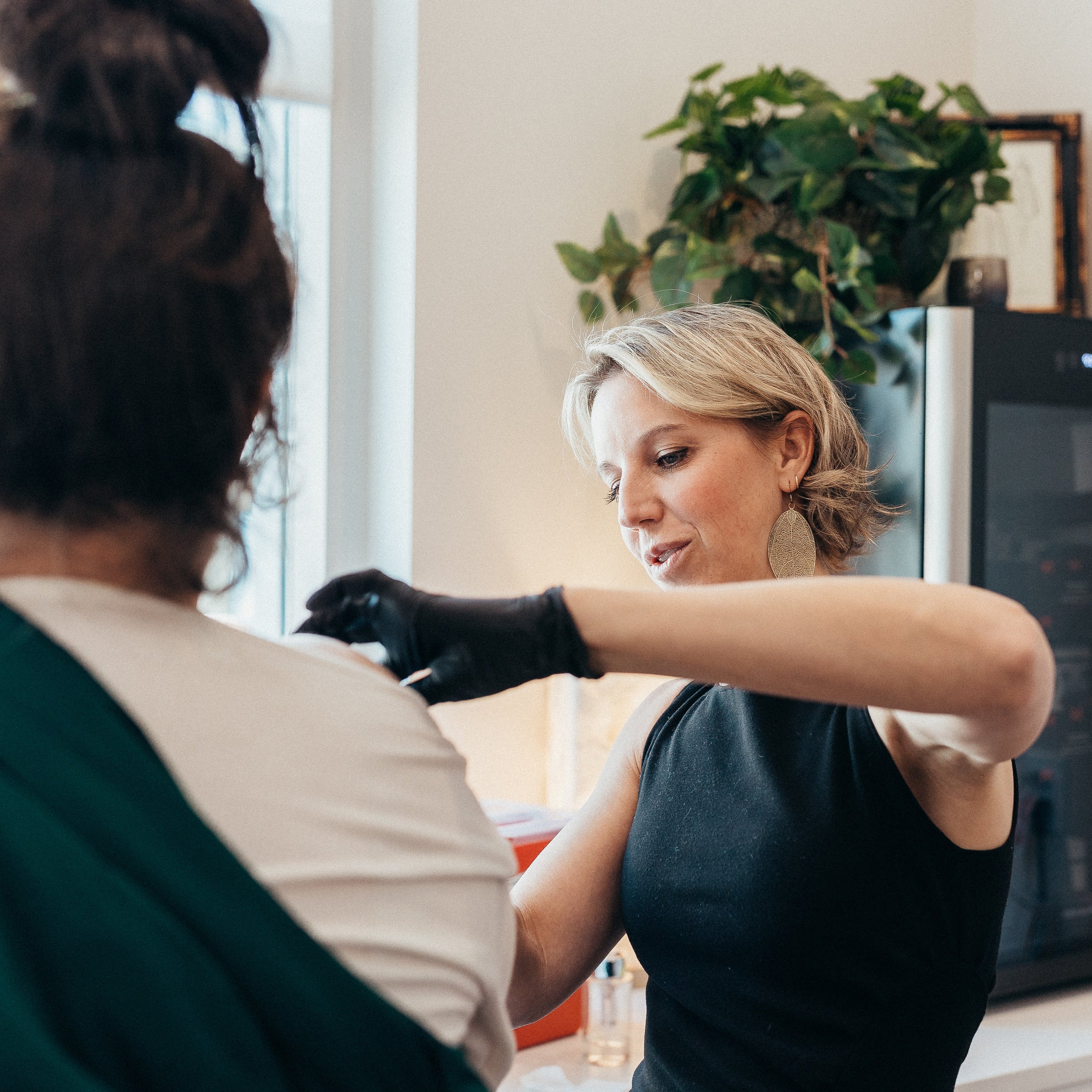 A registered nurse administers a B12 booster to a female guest in a luxury spa.