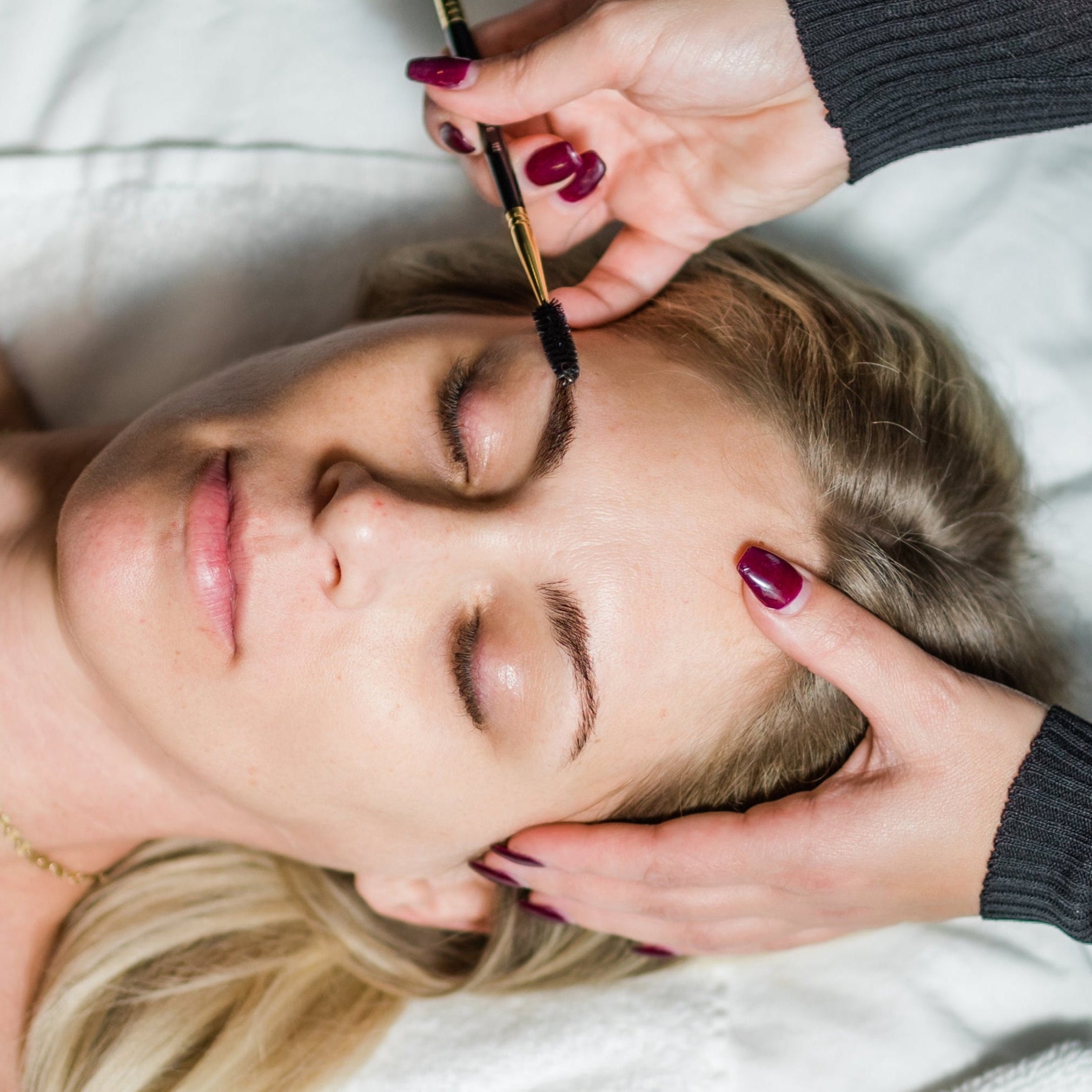 A woman relaxes with her eyes closed while receiving a brow lamination treatment at Pure Skin Wellness Spa