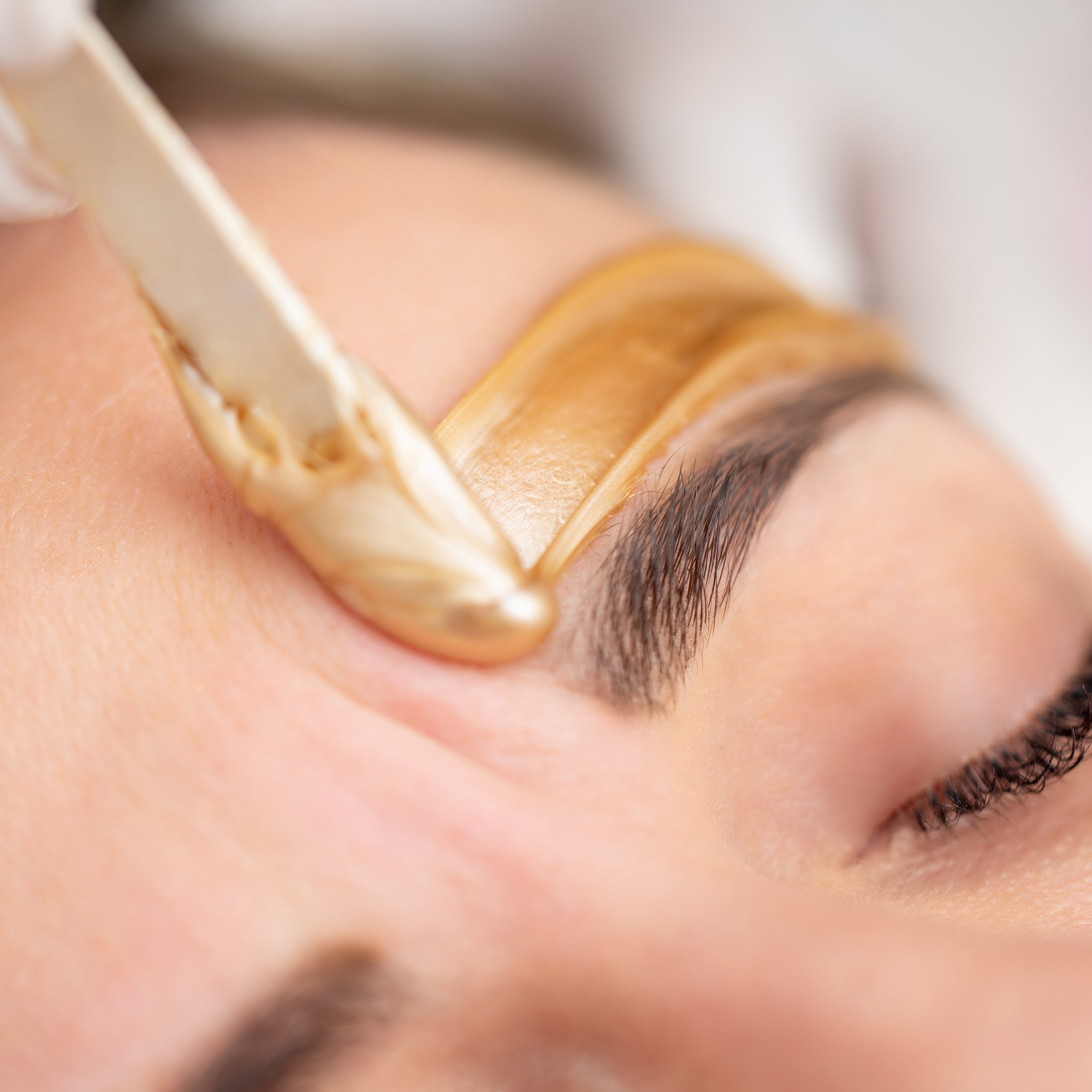 A close up of a woman's eyebrow receiving a brow waxing treatment