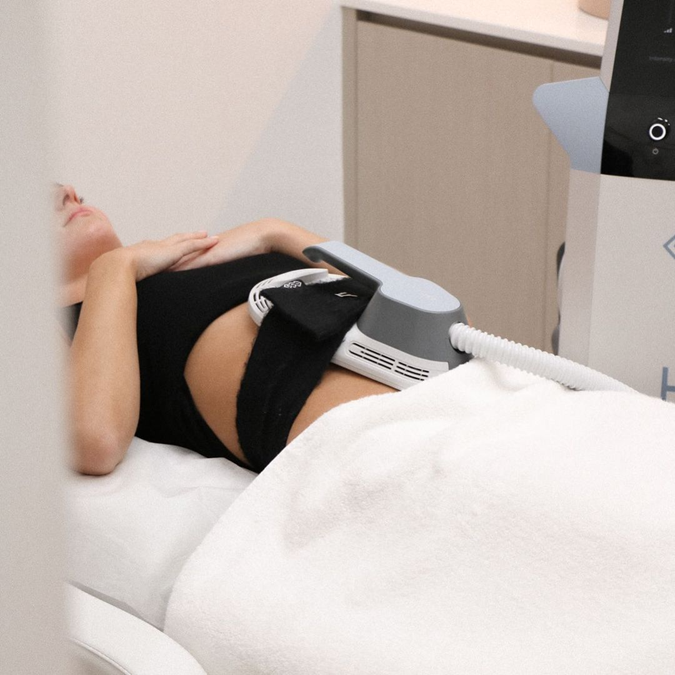 A woman relaxes in a luxury spa while receiving a giosculpt toning body treatment focused on her abdominal muscles.