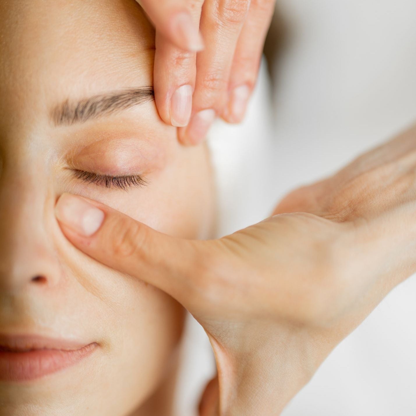 A woman relaxes while receiving a targeted facial massage with lymphatic benefits