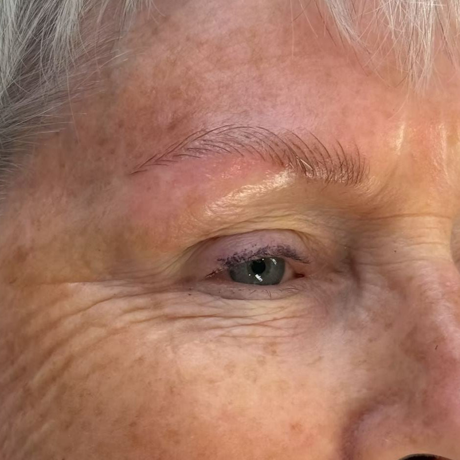 A close-up image of a woman's eye shows impactful results of a semi-permanent makeup treatment for microblading brows