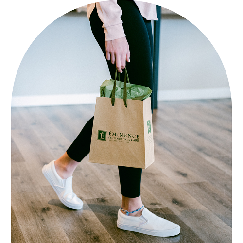 A guest walks out of a luxury spa carrying a shopping bag with a gift card for spa services.