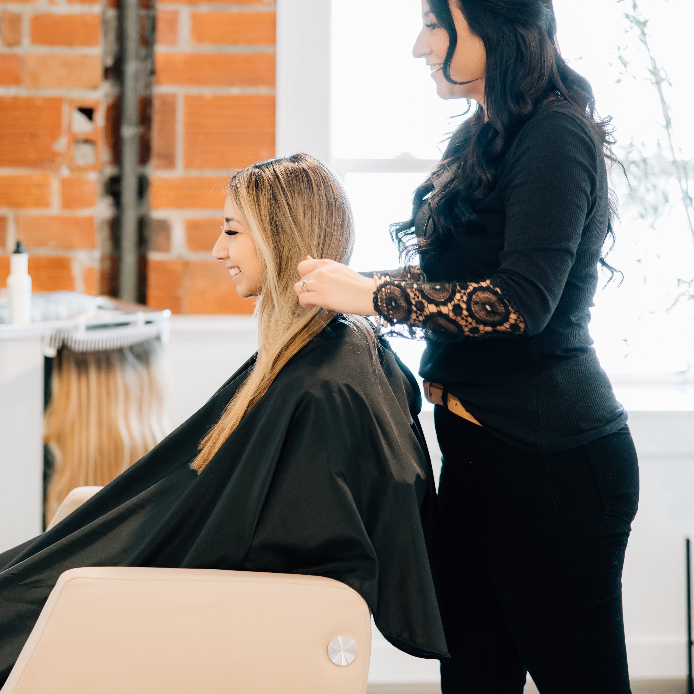 A professional hairstylist discusses hair styles with a spa guest as they prepare to color her hair.