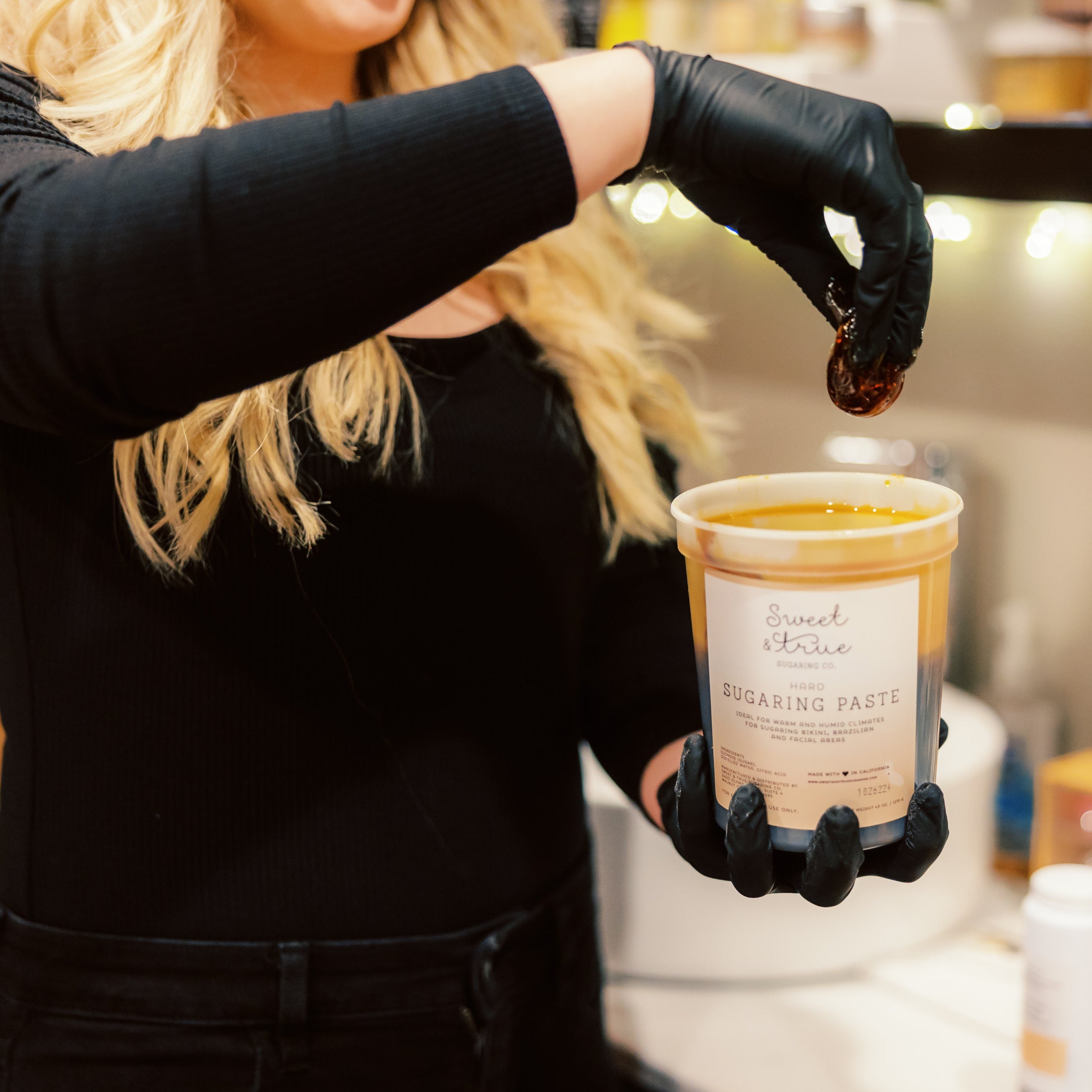 A close up of a female esthetician's hand hold sugaring paste
