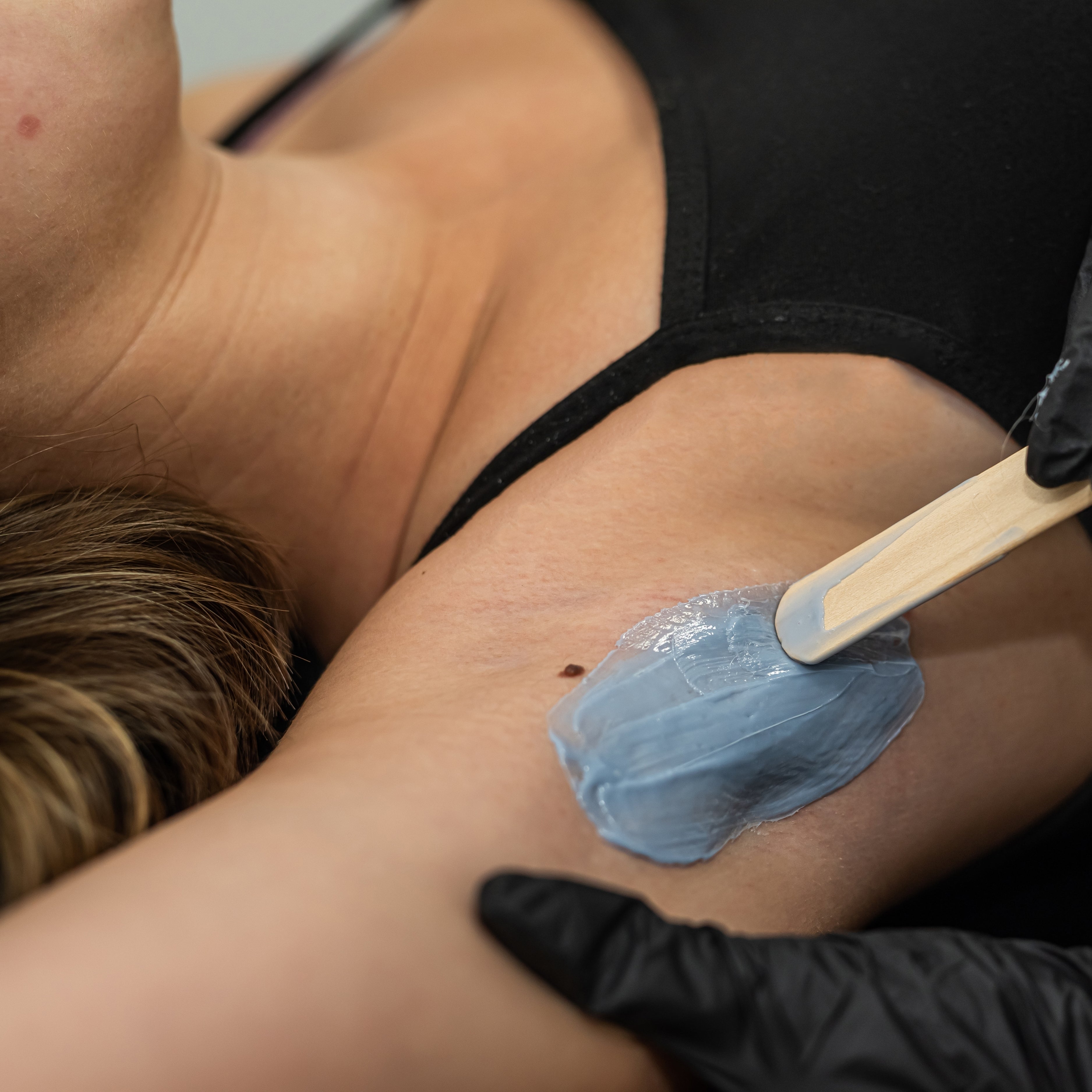 A close up of a woman's underarm receiving a waxing hair removal treatment