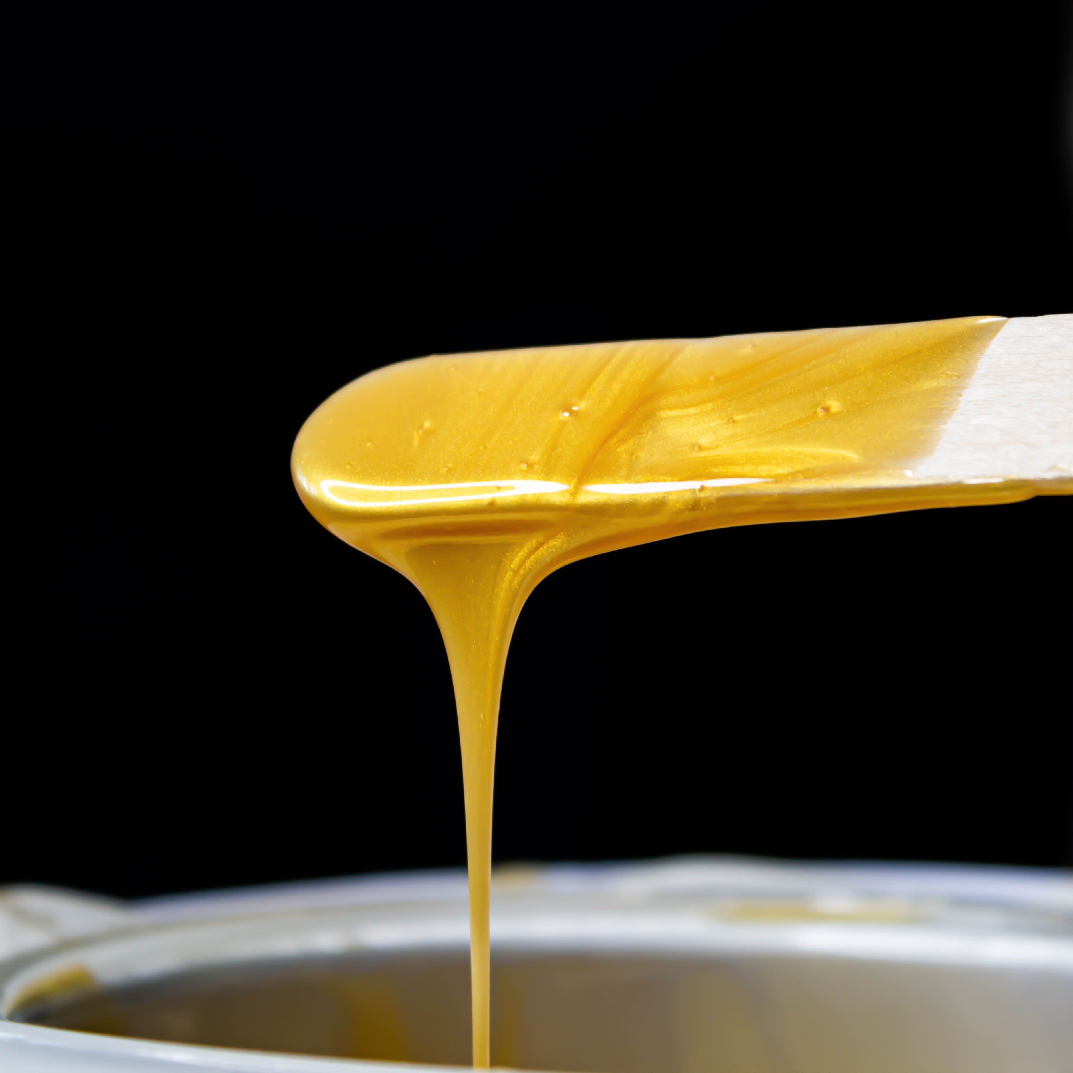 A close up of waxing dip stick with melted hair removal wax