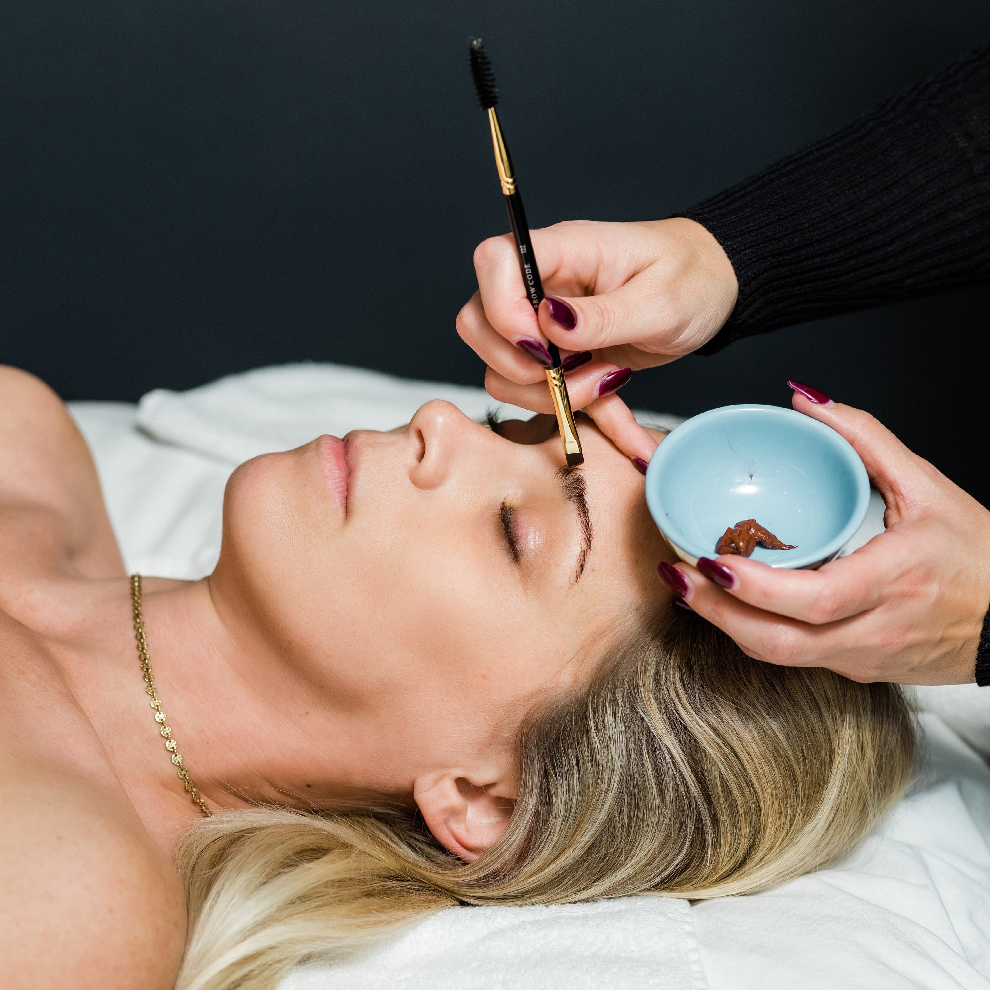 A woman relaxes with her eyes closed while receiving a brow tint at luxury spa Pure Skin Wellness Spa