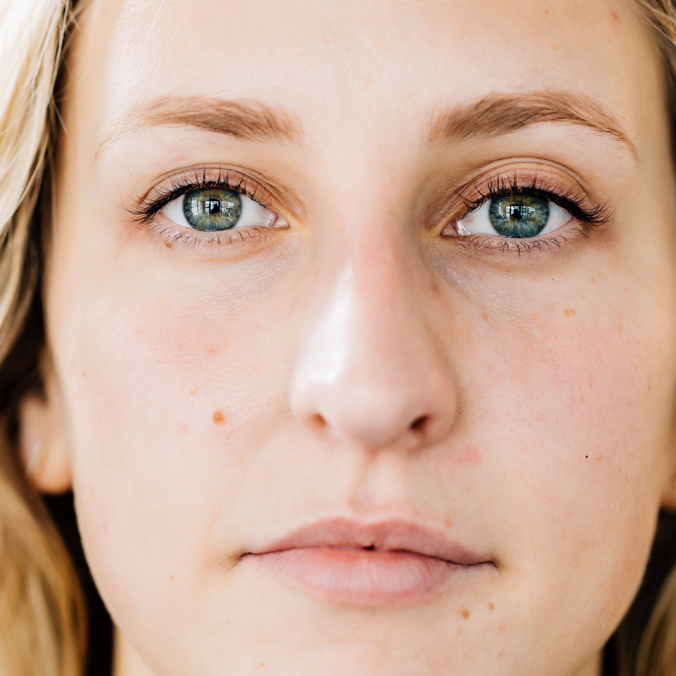 A woman looks directly into the camera, showing off the dramatic results of her lash lift and tint service.