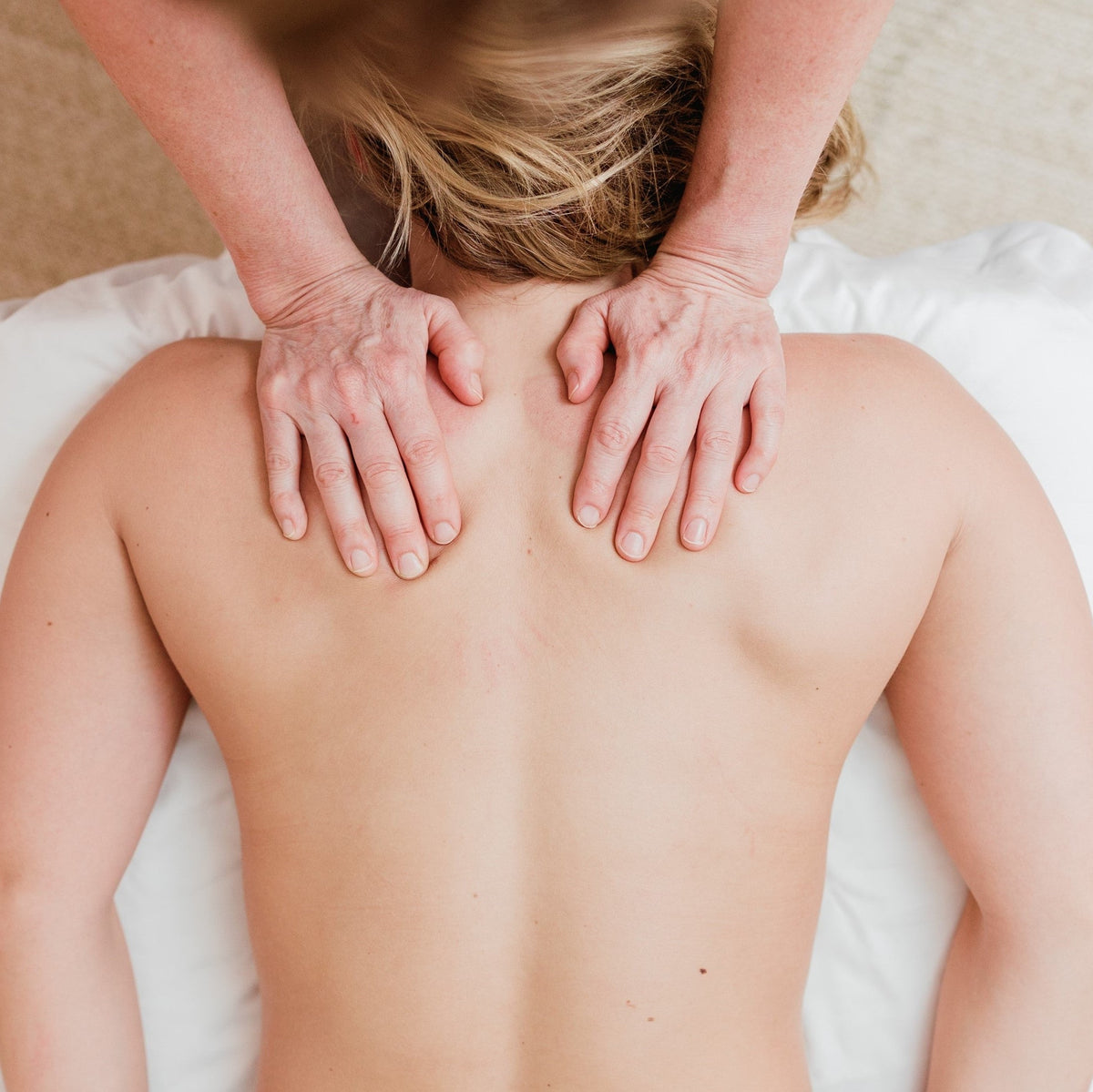 A woman relaxes while receiving a full body massage in a luxury spa setting.