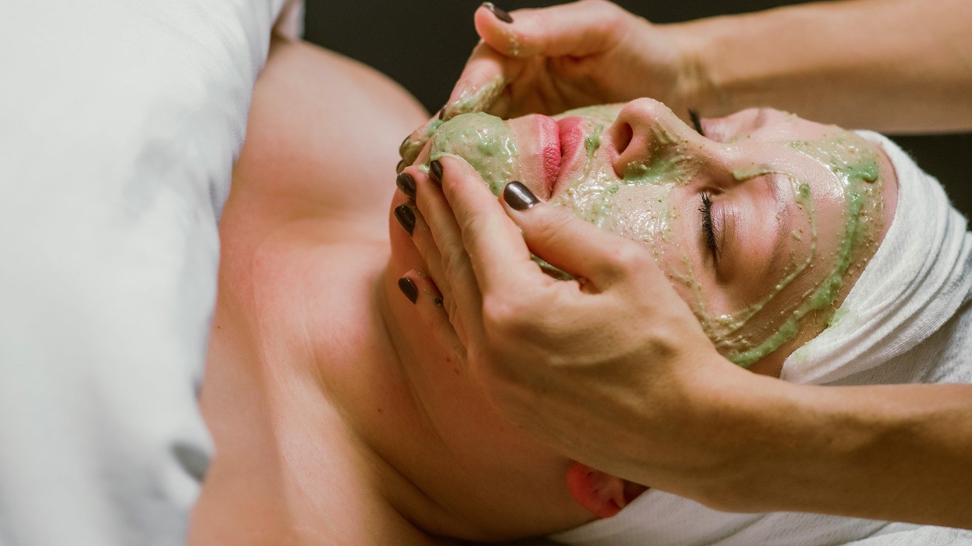 A woman relaxes while receiving a luxurious organic facial at the spa.