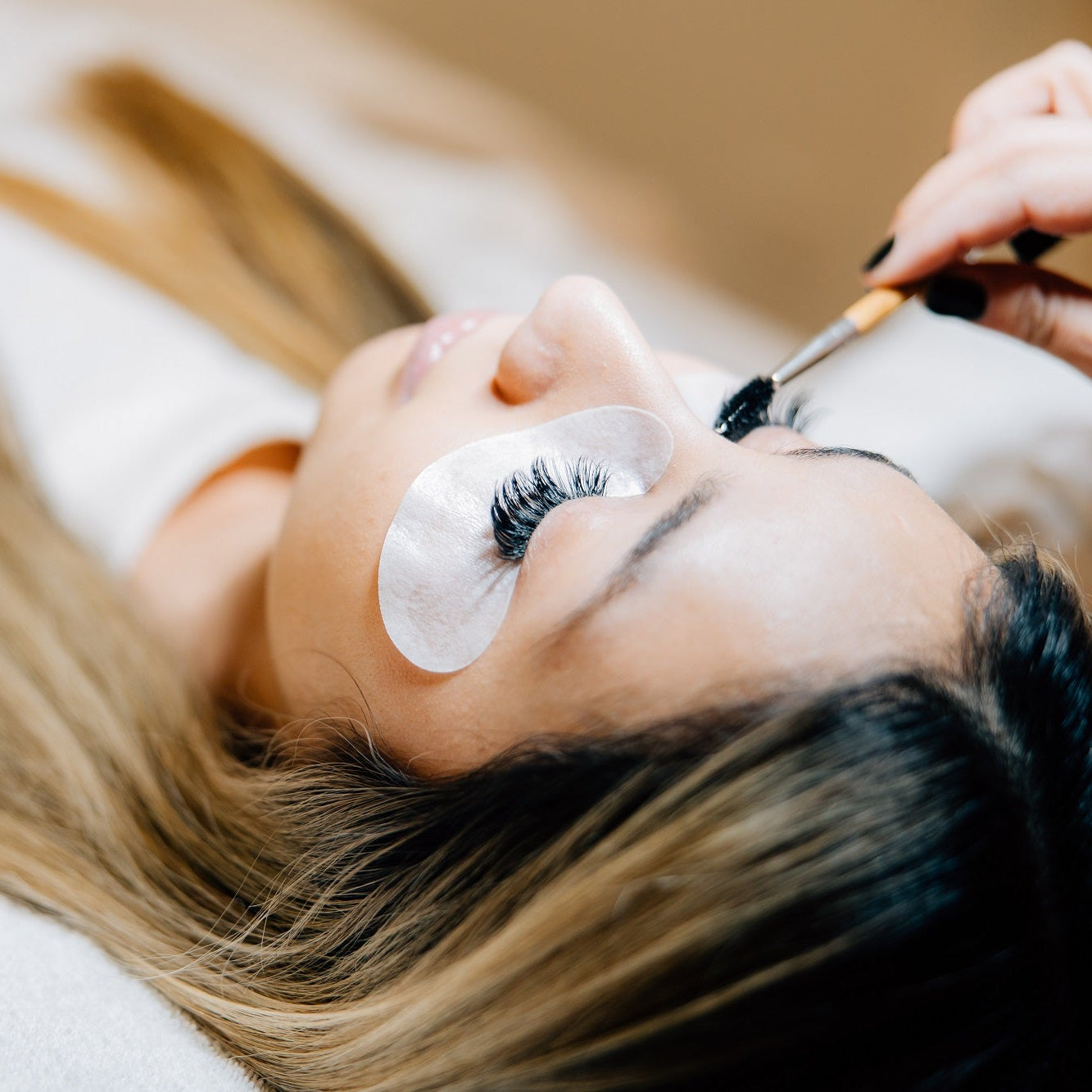 A woman relaxes while receiving a lash extension service in a luxury spa setting.